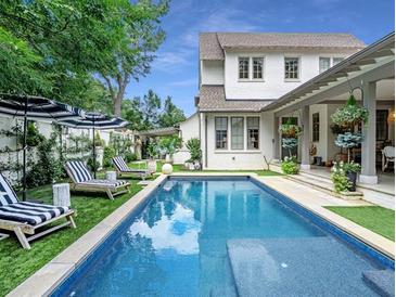 Backyard with a pool, striped lounge chairs, white fencing and a two-story white house at 405 9Th Ne St, Atlanta, GA 30309