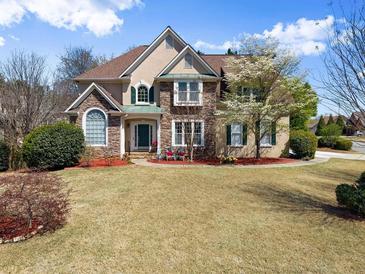 Charming two-story home with stone accents, a manicured lawn, and vibrant landscaping at 12350 Broadleaf Ln, Johns Creek, GA 30005