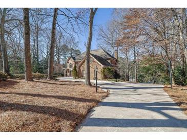 Long driveway leading to a two-story brick home with mature trees in a wooded setting at 7740 Sagebrush Dr, Atlanta, GA 30350