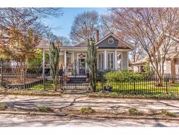 Charming bungalow-style home with inviting front porch and mature trees, framed by a decorative wrought iron fence at 1069 Colquitt Ne Ave, Atlanta, GA 30307