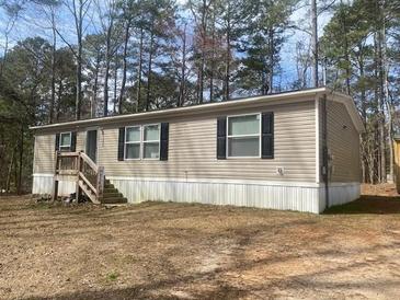 Tan single-story home with dark shutters surrounded by trees at 53 Oakview Dr, Carrollton, GA 30116