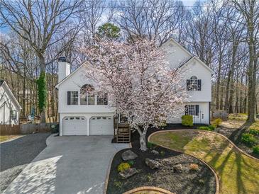 Charming two-story home with a well-manicured lawn and a beautiful flowering tree in the front yard at 210 Barrett Springs Way, Canton, GA 30115