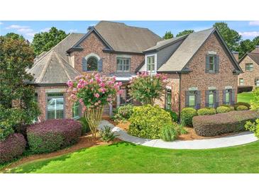 Beautiful brick home featuring a well-manicured lawn and landscaping with flowering trees and shrubbery at 3284 Kylee Dawn Cir, Lawrenceville, GA 30045