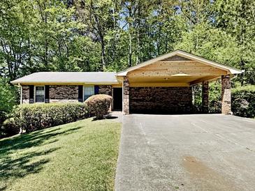 Charming brick home featuring a carport, lush lawn, and mature trees at 942 Ellison Ct, Austell, GA 30168