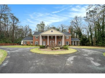 Stately brick home featuring a circular driveway and classic architectural details with large columns at 3074 Cascade Sw Rd, Atlanta, GA 30311