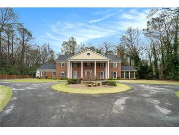 Stately brick home featuring a circular driveway, manicured lawn, and classic colonial design at 3074 Cascade Sw Rd, Atlanta, GA 30311