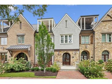 Charming townhomes showing a combination of stone and brickwork, complemented by lush green landscaping, arched doorway and small terraces at 55 Church St, Alpharetta, GA 30009
