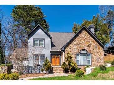 Charming two-story home featuring a stone facade, gray siding, and a well-manicured lawn with mature trees at 7445 Talbot Colony, Atlanta, GA 30328