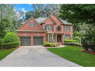 Charming two-story brick home with a well-manicured lawn and mature trees, offering great curb appeal and a welcoming ambiance at 5425 Edinbourgh Ct, Cumming, GA 30040