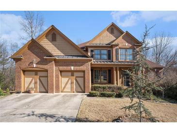 Charming brick home showcasing a three-car garage, complemented by manicured landscaping and a welcoming facade at 117 Olde Heritage Way, Woodstock, GA 30188