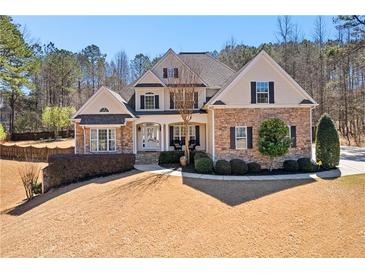 Beautiful two-story home featuring a stone and siding facade, manicured lawn, and mature trees at 340 Housman Dr, Fayetteville, GA 30215