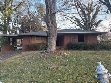 A single story brick home with a carport sits on a lot with mature trees needing some landscaping at 1713 Cahoon St, Atlanta, GA 30310