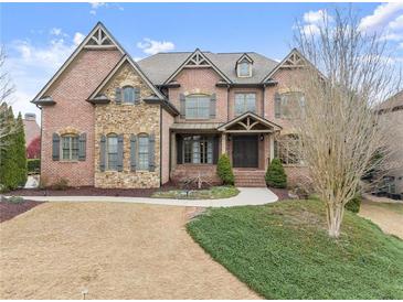 Beautiful two-story brick home featuring manicured landscaping, stone accents, and an elegant entrance at 6040 Boulder Bluff Dr, Cumming, GA 30040