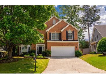 Charming two-story brick home featuring a well-manicured lawn, mature trees, and a two-car garage at 3242 Monarch Pine Nw Dr, Peachtree Corners, GA 30071