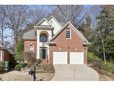 Traditional two-story brick home featuring a two-car garage and manicured front lawn at 535 Cameron Manor Way, Atlanta, GA 30328