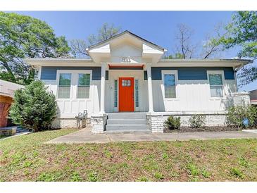 Charming home featuring an inviting orange front door, blue and white exterior, and landscaped front yard at 1497 Rogers Sw Ave, Atlanta, GA 30310