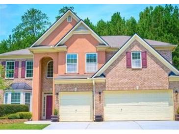 Stunning two-story home with a two-car garage, manicured lawn, and lush green trees in the background at 1172 Preserve Park Dr, Loganville, GA 30052