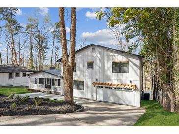 Charming two-story home with white siding, black trim, attached garage and a well-manicured front yard at 7410 Fields Dr, Cumming, GA 30041