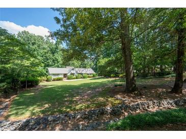 Spacious front yard of a charming home surrounded by mature trees and professional landscaping at 59 Woodlawn Dr, Marietta, GA 30067