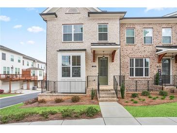 Charming brick townhome featuring a covered entrance, manicured lawn, and inviting curb appeal at 3260 Bennett Creek Ln, Suwanee, GA 30024
