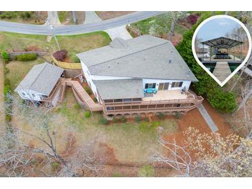 Stunning lakefront home featuring a large deck, boat dock, and a charming guest house, all set amidst a serene natural landscape at 5995 Lanier Heights Cir, Buford, GA 30518