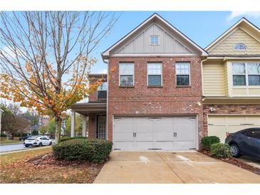 Charming two-story townhome with a brick facade and a two-car garage at 3879 Brockenhurst Dr, Buford, GA 30519
