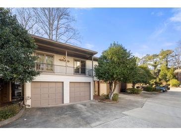Charming townhome featuring a two-car garage, a balcony, and mature trees surrounding the property at 303 Brandywine Cir, Atlanta, GA 30350