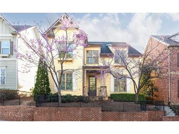 Charming two-story home with yellow siding, black trim and landscaped front yard and blooming trees at 232 Hunt Ne St, Marietta, GA 30060
