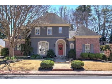 Charming two-story home featuring a unique gray stucco and brick exterior with a beautifully landscaped front yard at 2160 Kensington Gates Nw Dr, Kennesaw, GA 30152