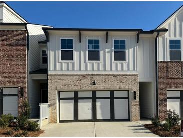 Beautiful townhouse showcasing modern farmhouse design with brick accents and a black-trimmed garage door at 264 Depot Landing Rd # 50, Auburn, GA 30011