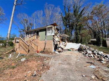 Damaged home exterior with debris scattered across the yard and driveway, in need of complete restoration or demolition at 3440 Corral Dr, Marietta, GA 30066