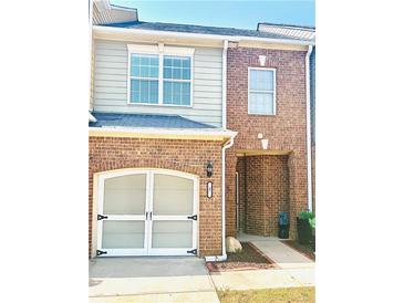 Charming townhome showcasing a brick facade, attached garage, and cozy front porch entry at 47 Trailside Cir, Hiram, GA 30141