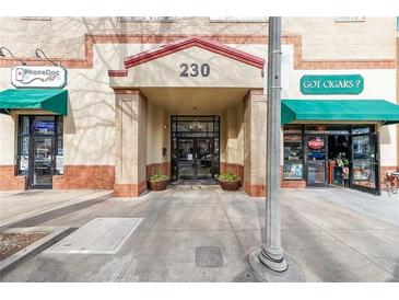 An inviting building entrance with brick pillars and decorative planters, complemented by nearby shops and awnings at 230 E Ponce De Leon Ave # 327, Decatur, GA 30030