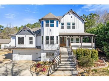 Two-story home showcasing a prominent front tower, gray roof, front porch, manicured landscaping, and an attached two-car garage at 695 Old Peachtree Rd, Lawrenceville, GA 30043