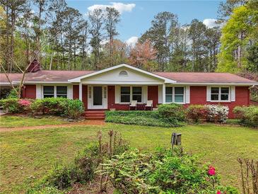 Charming red brick home with a well-manicured front lawn and blossoming azalea bushes at 738 Lauren Cir, Lawrenceville, GA 30043