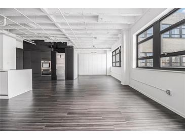 Spacious living room with large windows, wood floors, and a modern kitchen at 878 Peachtree Ne St # 711, Atlanta, GA 30309