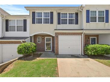 Charming townhome featuring a one-car garage, brick accents, and a well-maintained lawn at 695 Georgetown Ct, Jonesboro, GA 30236