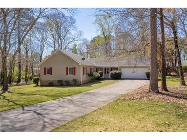 Charming ranch-style home with a well-maintained lawn, mature trees, and a long driveway leading to an attached garage at 2073 Lou Ct, Grayson, GA 30017