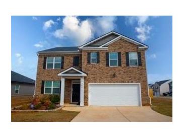 Two-story brick home featuring an attached two-car garage and manicured landscaping at 443 Faulkner St, Stockbridge, GA 30281