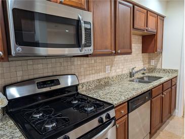 Well-lit kitchen with stainless steel appliances, granite countertops, and wood cabinets, perfect for cooking enthusiasts at 6980 Roswell Rd # E11, Atlanta, GA 30328