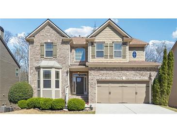 Charming two-story brick home with a well-manicured lawn and attached two-car garage at 1595 Johnstown Trace, Suwanee, GA 30024