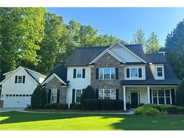 Charming two-story home featuring a stone and siding facade, manicured lawn, and an attached two car garage at 310 Persimmon Dr, Sharpsburg, GA 30277