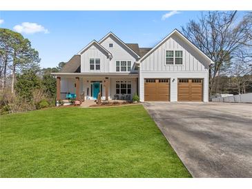 Charming two-story farmhouse with a well-manicured lawn, inviting front porch, and a two-car garage at 111 Franklin Rd, Woodstock, GA 30188