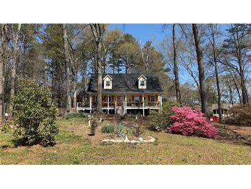 Charming two-story home featuring a front porch, inviting landscaping, and a yard filled with mature trees at 705 Mill Creek Rdg, Woodstock, GA 30188