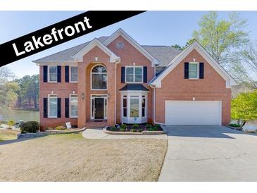 Stunning two-story brick home with lakefront views, black shutters, and a well-manicured lawn at 335 Lake Bluff Ct, Suwanee, GA 30024