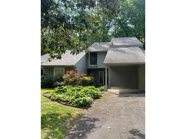 Charming home featuring a well-manicured lawn, flowering bushes, and a convenient covered carport at 165 Woodhaven Way, Alpharetta, GA 30009