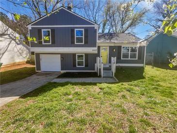 Charming two-story home features an attached garage, a well-manicured lawn and a yellow front door at 4665 Garden Hills Dr, Stone Mountain, GA 30083