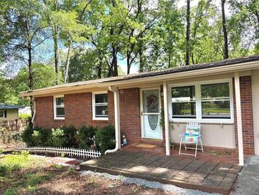 Charming brick home featuring a cozy front porch, manicured landscaping, and surrounded by mature trees at 877 Verona Dr, Clarkston, GA 30021