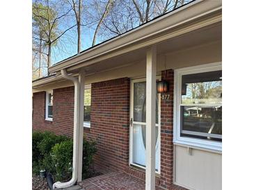 Exterior of a brick home with a front door with brick pavers, white trim, and a storm door at 877 Verona Dr, Clarkston, GA 30021