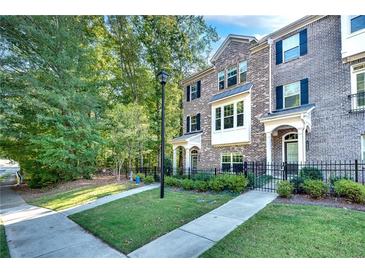 Charming brick townhome with manicured front lawn and black wrought iron fence at 1007 Belle Ave, Roswell, GA 30076